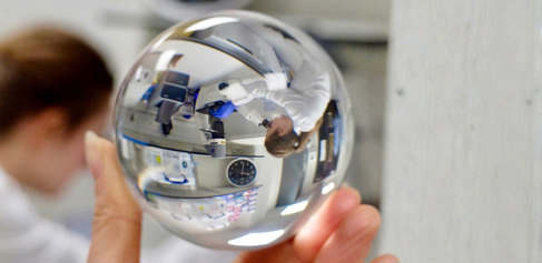 Image of student looking through microscope, reflected through a glass orb