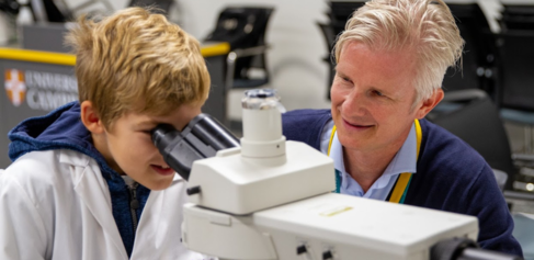 Matt Zilbauer and a young person at the microscope