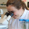 Dr Alecia-Jane Twigger looking through microscope