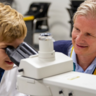 Matt Zilbauer and a young person at the microscope